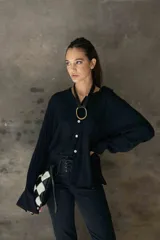 Camisa de corte relajado y caída fluida, con cuello clásico, mangas largas con puños anchos y cierre frontal con botones a contraste.