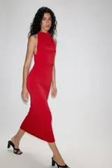 Vestido largo de corte fluido con cuello halter y espalda descubierta. Presenta un detalle de drapeado lateral y bajo recto.