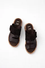 Sandalia tipo slide de cuero color marrón oscuro, con dos tiras ajustables sobre el empeine. La tira superior es de gamuza y la inferior tiene textura de cocodrilo. La plantilla es acolchada y forrada en cuero.