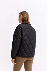 Campera matelaseada de diseño en rombos color verde oliva, con cuello y bordes en contraste color marrón. Presenta cierre frontal con botones a presión, mangas largas con puños elásticos y corte holgado.