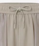 Bermuda deportiva color verde oliva, con cintura elástica, cordón interior, bolsillos laterales y logo reflectante en la pierna izquierda.