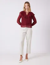 Blusa de encaje color beige, marca Cupio, con cuello a la base y escote en V con lazo de ajuste. Presenta una sobrecapa de encaje con aplique de puntilla y mangas largas de encaje floral translúcido, terminadas en puños elásticos con volado. Incluye forro interno a tono.