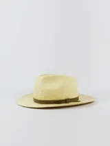 Sombrero de paja tipo australiano, color beige, con cinta marrón oscura decorativa alrededor de la copa y detalle de placa metálica con la marca.