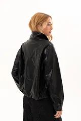 Campera de cuero sintético color negro, con cierre frontal, cuello clásico y bolsillos laterales con broches metálicos.