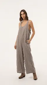 Mono de lino color marrón, de diseño relajado con escote en V pronunciado, breteles anchos, bolsillos laterales y pantalón de pierna amplia.