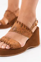 Sandalia de taco chino y plataforma forrada, confeccionada 100% en cuero color tostado con acabado metalizado texturizado en la capellada y detalles de costuras artesanales. Cuenta con doble tira superior y tira trasera ajustable con hebilla metálica.