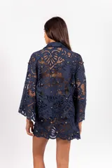 Camisa de molde clásico confeccionada en encaje bordado tipo guipur, color azul, con mangas largas amplias y aplicación de tachas doradas.