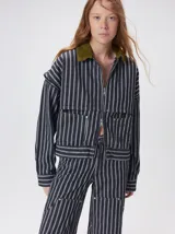 Campera de denim a rayas verticales con cuello de pana en color bordó. Presenta cierre frontal, mangas desmontables con cierre en los hombros, canesú en el pecho y bolsillos de parche cuadrados.