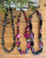 Conjunto de collares de cuentas de diferentes colores y materiales, incluyendo cuentas de piedra, madera y cristal. Los collares tienen cadenas doradas y etiquetas blancas con la marca "MANDRA".