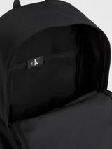 Mochila negra Calvin Klein Jeans con bolsillo frontal y logo estampado en blanco.