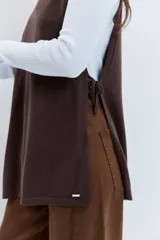 Poncho asimétrico de tejido de punto en color marrón, con cuello alto tipo polera y diseño sin mangas con aberturas laterales.