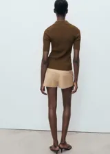 Jersey de punto fino color marrón, con cuello camisero, manga corta y cierre frontal con botones pequeños.