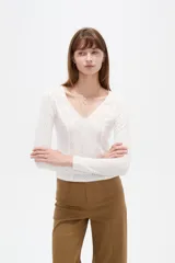 Remera negra de manga larga y calce al cuerpo, confeccionada en poliéster con diseño calado y escote en V.