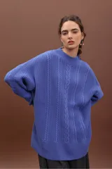 Sweater de punto negro con diseño de trenzas verticales, cuello alto y corte holgado de estilo oversize.