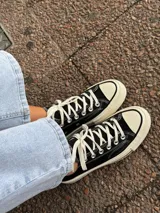 Zapatillas bajas de lona color blanco, con cordones marrones, puntera de goma y base blanca.