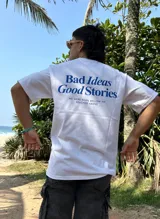 Remera blanca de algodón con estampa azul en la espalda con la frase "Bad Ideas Good Stories".