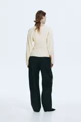 Remera de punto fino suave color beige, con escote en V, cintura entallada y mangas dolman largas.
