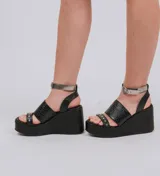 Sandalias de plataforma y taco chino negro con textura símil serpiente en la capellada, tira delantera con tachas metálicas y tira al tobillo plateada con hebilla de ajuste.