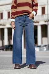 Pantalón de jean estilo wide leg con tiro medio, confeccionado en denim con elastano. Presenta un lavado azul clásico, cierre frontal con botón y bolsillos laterales.