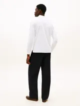 Chomba de manga larga color blanco, con cuello polo y cartera de dos botones. Cuenta con un pequeño logo bordado de Tommy Hilfiger en el pecho y corte regular.