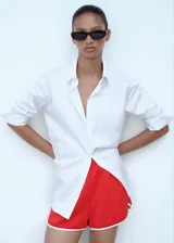 Short deportivo de corte recto, color rojo con ribetes blancos en contraste en los bordes inferiores. Cuenta con cintura elástica y bolsillos laterales.