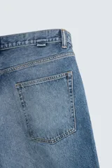 Bermuda de denim de algodón, color azul medio lavado, de corte ancho (baggy fit) y largo hasta la rodilla. Presenta cinco bolsillos y cierre frontal con cremallera y botón.