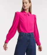 Camisa celeste de crepé con cuello inglés, manga larga abullonada y abotonadura frontal.