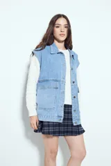 Chaleco de jean con corte oversized, diseño sin mangas, cuello camisero, cierre frontal con botones metálicos y bolsillos frontales tipo cargo.