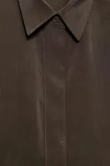 Camisa de manga corta y corte fluido, color marrón, con cuello solapa y cierre frontal con botones ocultos. Presenta bajo asimétrico con aberturas laterales y mangas con vuelta.