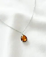 Collar con cadena plateada y dije de cristal color ámbar en forma de lágrima.