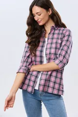 Camisa holgada a cuadros en tonos rosado, azul marino y blanco, de manga larga con puños ajustables, cuello camisero y cierre frontal de botones.
