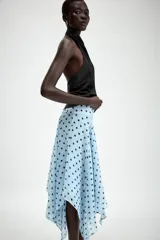 Falda midi de tiro medio color celeste con estampado de lunares negros, diseño asimétrico y forro interior. Cuenta con cierre lateral de cremallera oculta.