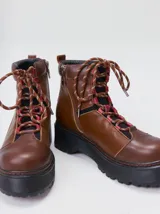 Bota de estilo trekking con diseño multicolor en tonos marrón, azul y detalles en rojo. Presenta plataforma de goma dentada, cordones tipo cuerda de escalada y cuello acolchado.