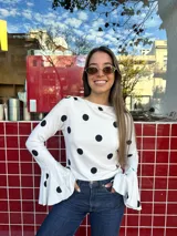 Blusa al cuerpo color blanco con estampado de lunares negros, cuello redondo y mangas largas con terminación acampanada.