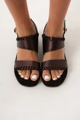 Sandalias de cuero color marrón con plataforma y taco de cuña forrado en gamuza negra. Presentan dos tiras anchas con detalle de pespuntes en el borde y hebilla dorada en la tira del tobillo.