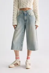 Jean culotte estilo bermuda de tiro bajo, color celeste con efecto desgastado, perneras amplias y corte recto por debajo de las rodillas.