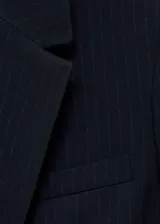 Chaqueta de corte recto y diseño estructurado con estampado de raya diplomática. Presenta cuello con solapa, cierre frontal de dos botones, manga larga con puños abotonados, un bolsillo de ribete en el pecho y dos bolsillos laterales con solapa.