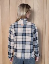 Camisa de manga larga con estampado de rayas verticales en tonos blanco y lila. Presenta cuello alto con volados, cierre frontal con doble botonadura y puños con volados.