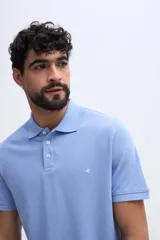 Remera polo verde militar de algodón pima, con cuello y puños acanalados, cierre frontal de tres botones y pequeño bordado de ave en el pecho.