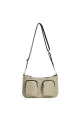 Bandolera de diseño utilitario en color beige, con dos bolsillos frontales externos, cierre principal y correa ajustable. Presenta detalles en color lila en los tiradores de los cierres y logo de la marca estampado.