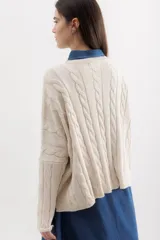 Sweater de punto con diseño de trenzas verticales, cuello redondo y corte holgado. Presenta una etiqueta de cuero sintético con el logo de la marca en la parte inferior.