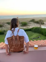 Mochila de cuero marrón con cierre superior y múltiples bolsillos externos. Se puede convertir en bolso de mano o bandolera gracias a sus correas ajustables y extraíbles.