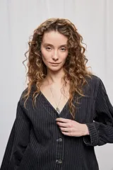 Campera de denim con diseño a rayas verticales y calce recto. Presenta escote en V, cierre frontal con botones metálicos y mangas largas.