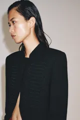 Blazer negro ZW Collection con cuello perkins, manga larga con vuelta en los puños y bajo asimétrico. Presenta detalles de alamares bordados en el frente.