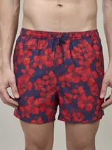 Short de baño con estampado floral en tonos rojos sobre fondo azul marino, con cintura elástica y cordón ajustable.