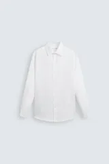 Camisa blanca de manga larga con cuello italiano y cierre frontal de botonadura. Presenta un tejido con estructura de fácil cuidado y un calce regular.