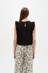 Blusa de algodón negra sin mangas, con cuello a la base, volados en los hombros y detalles de encaje y calados frontales.
