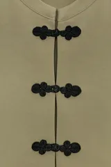 Top negro de manga corta y cuello redondo, con cierre frontal de alamares decorativos.