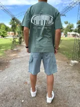 Remera oversize verde militar con estampado gráfico en la espalda con el texto "TOPSTYLE COLLECTIONS EST 2021".