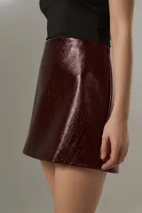 Minifalda de cuero sintético color borgoña, de tiro alto y corte al cuerpo.